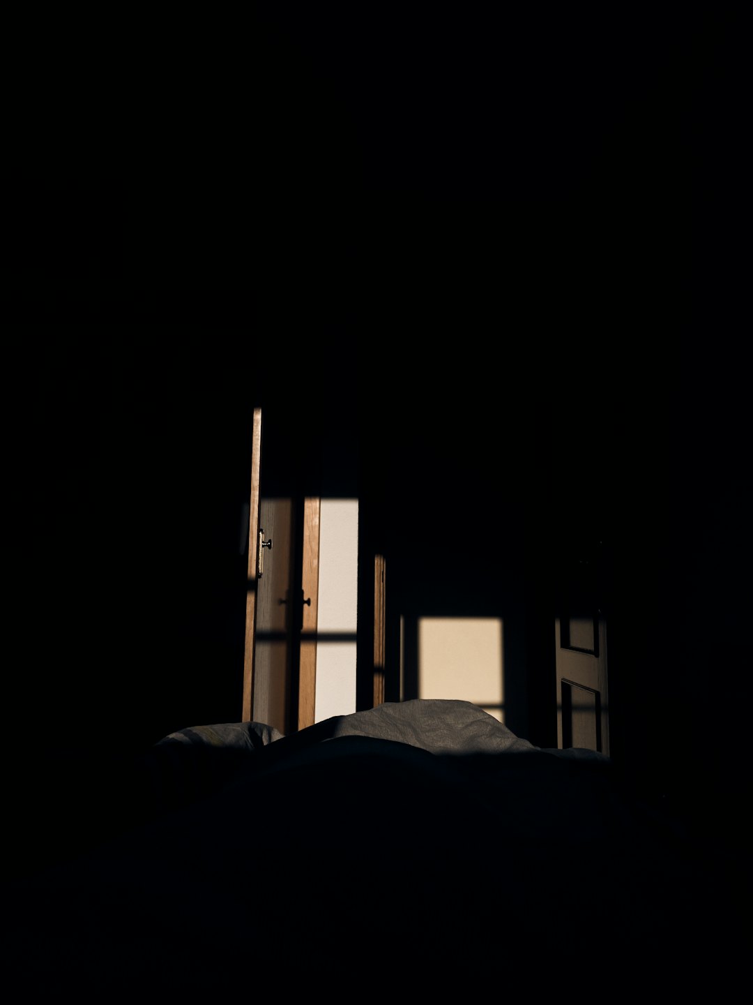 La luz del sol entra por una puerta entreabierta a una habitación oscura.