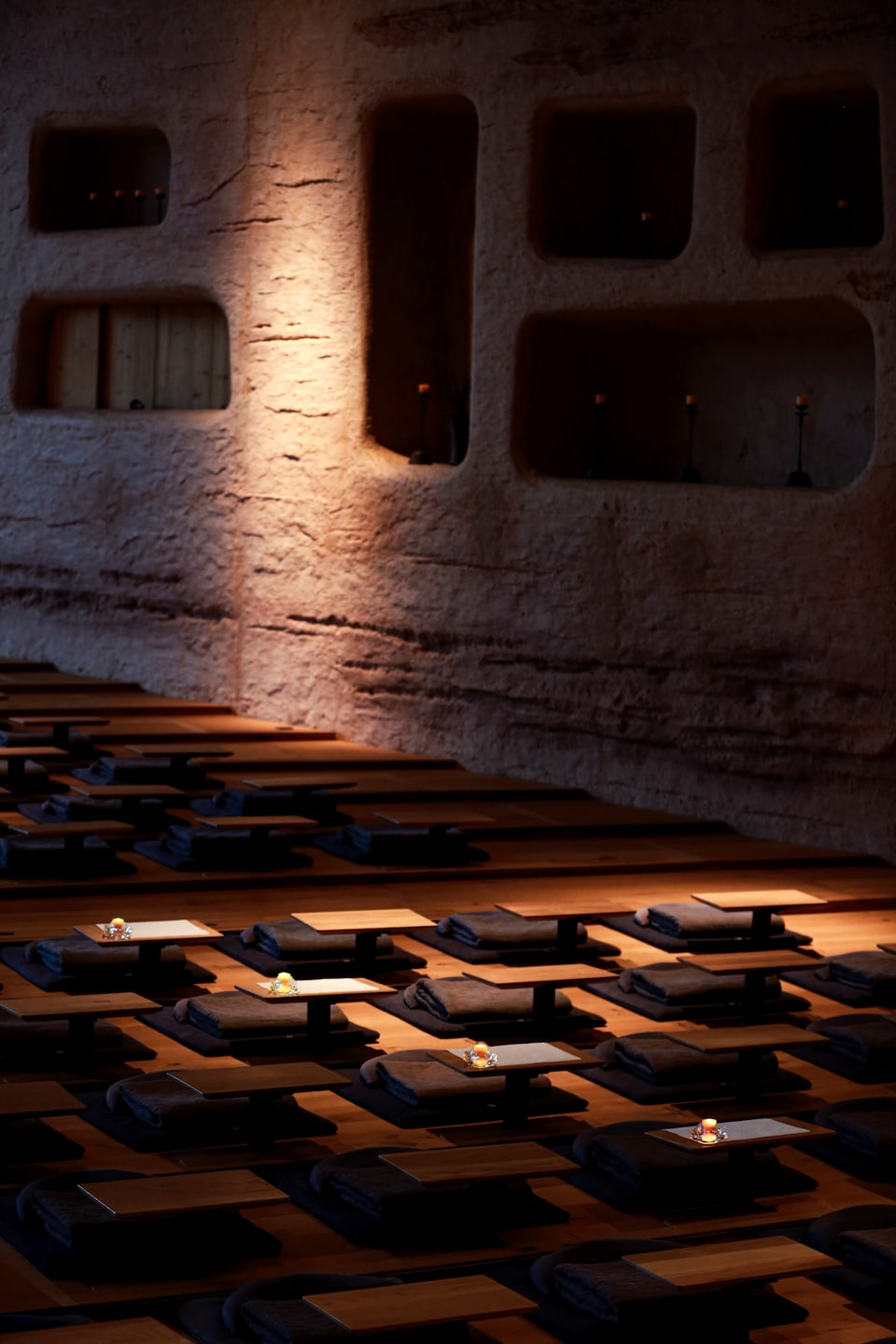 Sala de meditación vacía con cojines y velas en el suelo.
